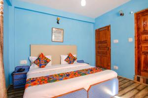a bedroom with a bed with blue walls at FabHotel Orchard Retreat in Manāli