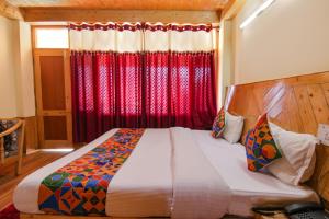 a bedroom with a bed with a red curtain at FabHotel Orchard Retreat in Manāli