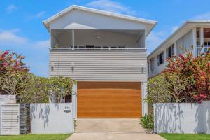 布里斯班On Esplanade own flat & Pool, Manly cafe precinct的一个带木制车库门的度假屋