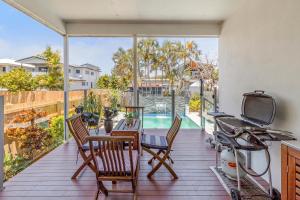 einen Balkon mit einem Tisch und Stühlen sowie einem TV in der Unterkunft On Esplanade own flat & Pool, Manly cafe precinct in Brisbane