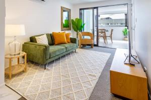 a living room with a green couch and a table at Heart of Christchurch CBD Hideaway 2bed 1 bath in Christchurch