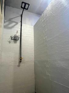 a shower in a bathroom with a white wall at Good Feeling Hostel in Banyuwangi