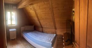 a small bed in a wooden room with a window at Ferienhaus Kobolzeller Schlößchen a.d.Weinsteige in Rothenburg ob der Tauber