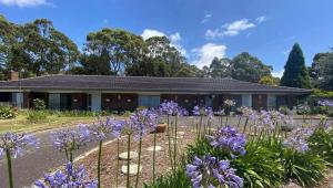 una casa con flores púrpuras delante de ella en Heavenly Farm B & B Tasmania, en Boat Harbour