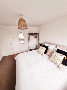 um quarto com uma grande cama branca com almofadas em 2 Bed Cosy Aylesbury House with Parking em Buckinghamshire