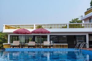 a pool with chairs and umbrellas next to a building at SPARV Aulakhs Resort in Mandrem