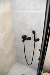 a shower with a black shower head in a bathroom at Polles Εlies Cozy Αpartment in Egina