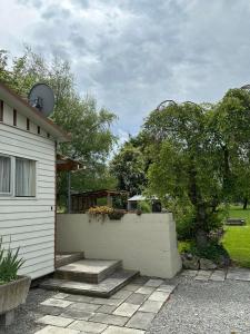 a white house with a retaining wall and a fence at Burkes Pass Country Motels in Burkes Pass