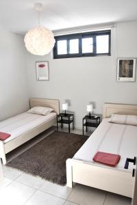 two beds in a room with two tables and a chandelier at Polles Εlies Cozy Αpartment in Aegina Town
