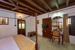 a bedroom with a bed and a table and a chair at Malabar Kovilakam in Malappuram