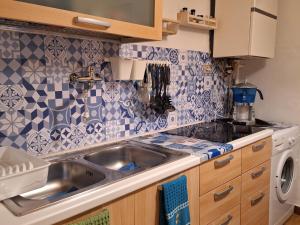 uma cozinha com lavatório e azulejos azuis e brancos em Michelle Apartment em Bari