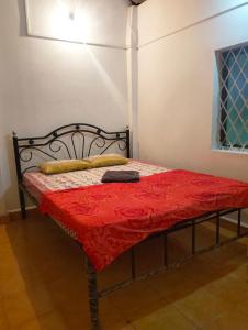 a bed with a red comforter in a room at Anika homes in Canacona