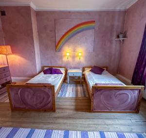 two beds in a room with a rainbow on the wall at Fridhem Coursecenter & Guesthouse in Stjärnsund