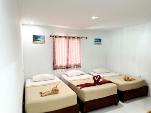 een kamer met drie bedden met knuffels erop bij Bang sit Guest House in Phi Phi Don