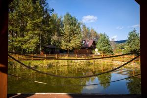 a view of a pond with a house in the background at Glamping Pod Gwiazdami in Pietrusza Wola