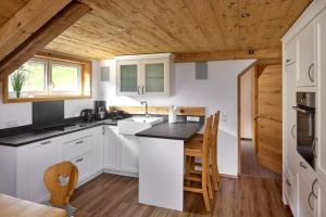a kitchen with white cabinets and a wooden ceiling at Alpenhaus Montafon in Gargellen