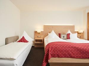 um quarto de hotel com duas camas com lençóis vermelhos e brancos em Landhotel Mohren em Schwarzenbach