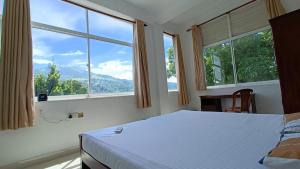 a bedroom with a bed and two large windows at Smile Hub Kandy in Kandy