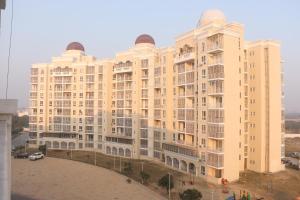 a large beige building with a parking lot in front of it at Sridham Holiday Vrindavan in Vrindāvan