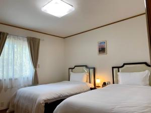 two beds in a hotel room with a window at Chateau Ange UMAYA - Vacation STAY 68831v in Tsumagoi