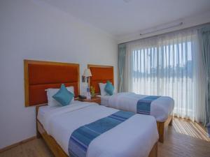 ein Hotelzimmer mit zwei Betten und einem Fenster in der Unterkunft Hotel Bodhiz TUSAL in Kathmandu