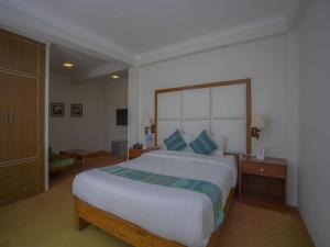 sypialnia z dużym białym łóżkiem z niebieskimi poduszkami w obiekcie Hotel Bodhiz TUSAL w Katmandu