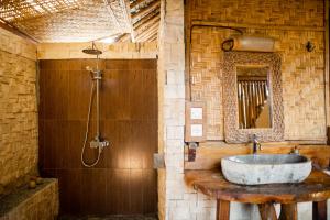 a bathroom with a stone sink and a shower at Rinjani Lighthouse in Senaru