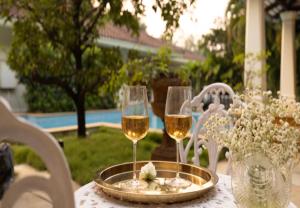 uma mesa com dois copos de vinho e flores em Emerald Leaf - Villa Frangipani em Dahanu