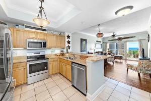 a kitchen with wooden cabinets and appliances and a living room at Crystal Tower 404 in Gulf Shores
