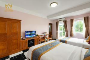 Luxy Park Hotel & Residences - Phu Quoc City Centre في فو كووك: غرفة فندقية بسريرين وتلفزيون بشاشة مسطحة