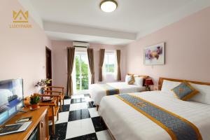 a hotel room with two beds and a flat screen tv at Luxy Park Hotel & Residences - Phu Quoc City Centre in Phu Quoc