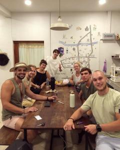 um grupo de pessoas sentadas em torno de uma mesa de madeira em Together Backpackers Hostel em Chiang Rai