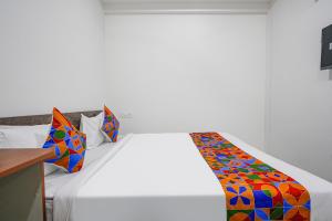a bedroom with a white bed with a colorful blanket at FabHotel Rooms 27 in Hyderabad