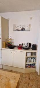une cuisine avec des placards blancs et une étagère avec de la vaisselle dans l'établissement Weilheimer Ferienparadies, à Weilheim in Oberbayern