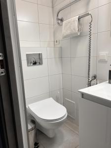 a white bathroom with a toilet and a sink at Pas Loretą Apartments in Palanga