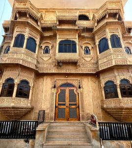 a large building with a wooden door and stairs at Hotel Pol Haveli Jaisalmer in Jaisalmer