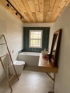 a bathroom with a tub and a sink and a mirror at Yellowwoods Farm - WILLOUGHBYS COTTAGE and OLD STABLES COTTAGE in Curryʼs Post