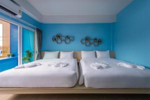 2 łóżka w pokoju z niebieskimi ścianami w obiekcie Otter House Aonang Intersection w mieście Krabi