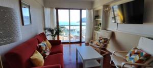 a living room with a red couch and a view of the ocean at Mundaka Izaro Eye in Mundaka