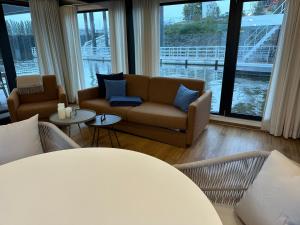 salon z kanapą, krzesłami i oknami w obiekcie Hausboote am Lankenauer Höft w Bremie