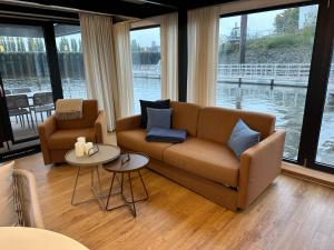 ein Wohnzimmer mit einem Sofa, 2 Tischen und Fenstern in der Unterkunft Hausboote am Lankenauer Höft in Bremen