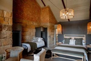 a bedroom with two beds and a stone wall at Andes Clarens Guesthouse in Clarens