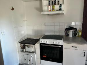 Il comprend une petite cuisine équipée d'une cuisinière et d'appareils électroménagers blancs. dans l'établissement Nice red cottage near the lake Hjalmaren and Vingaker, à Vingåker