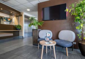 een wachtkamer met twee stoelen en een tv aan de muur bij B&B HOTEL Niort Marais Poitevin in Niort