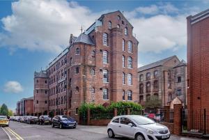 a large brick building with cars parked in front of it at Stylish 1-Bed Studio - Heart of Nottingham in Nottingham
