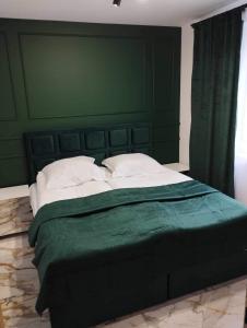 ein großes Bett mit einem grünen Kopfteil und weißen Kissen in der Unterkunft Apartament Zielony 12/2 in Starogard Gdański