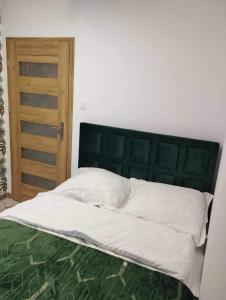 1 cama con cabecero verde y puerta de madera en Apartament Zielony 12/2, en Starogard Gdański