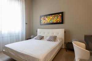 una camera con un letto bianco e un dipinto sul muro di Deluxe apartment Milia Agrigento a Agrigento