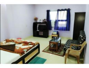 a bedroom with a bed and a chair and a table at Hotel Anjali, Deoghar in Deoghar