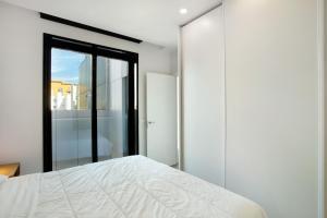 a bedroom with a white bed and a window at Penthouse Aliseo on the beach in Las Palmas de Gran Canaria